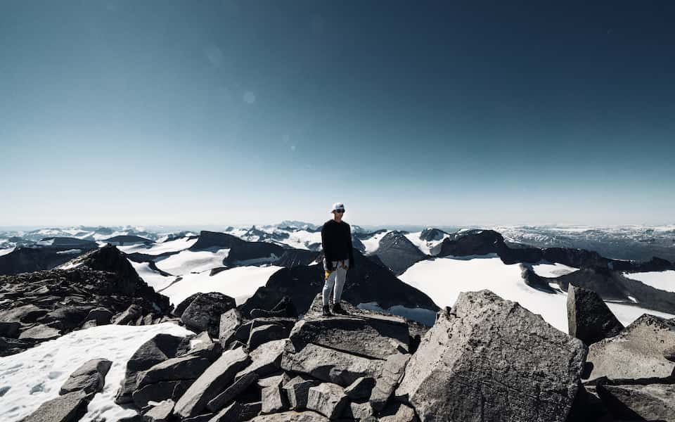 Harald Revery standing at Galdhøpiggen top with Jotunheimen behind him.